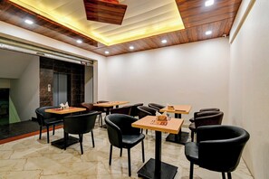 Een restaurant met meerdere tafels en stoelen, een houten plafond en een marmeren vloer.