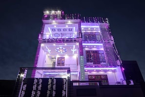 A multi-story building with illuminated signage and decorative lighting. - Townhouse Relax Inn (Lucknow)