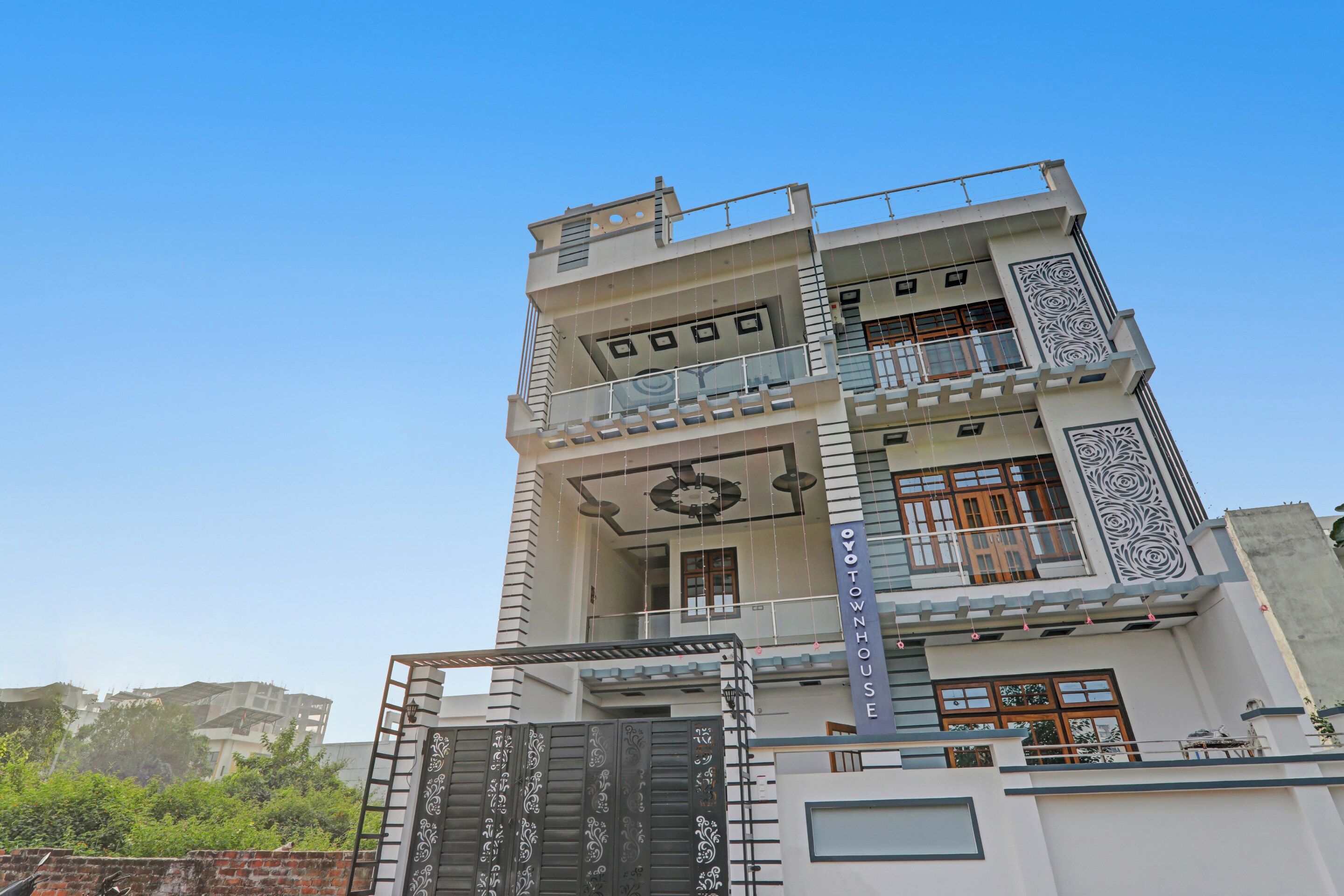 A multi-story building with a balcony on the second floor, a decorative gate, and a sign reading 'OYO TOWNHOUSE'.