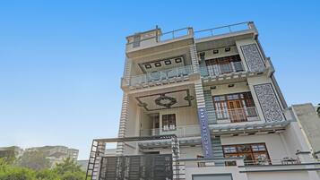 A multi-story building with a balcony on the second floor, a decorative gate, and a sign reading 'OYO TOWNHOUSE'.