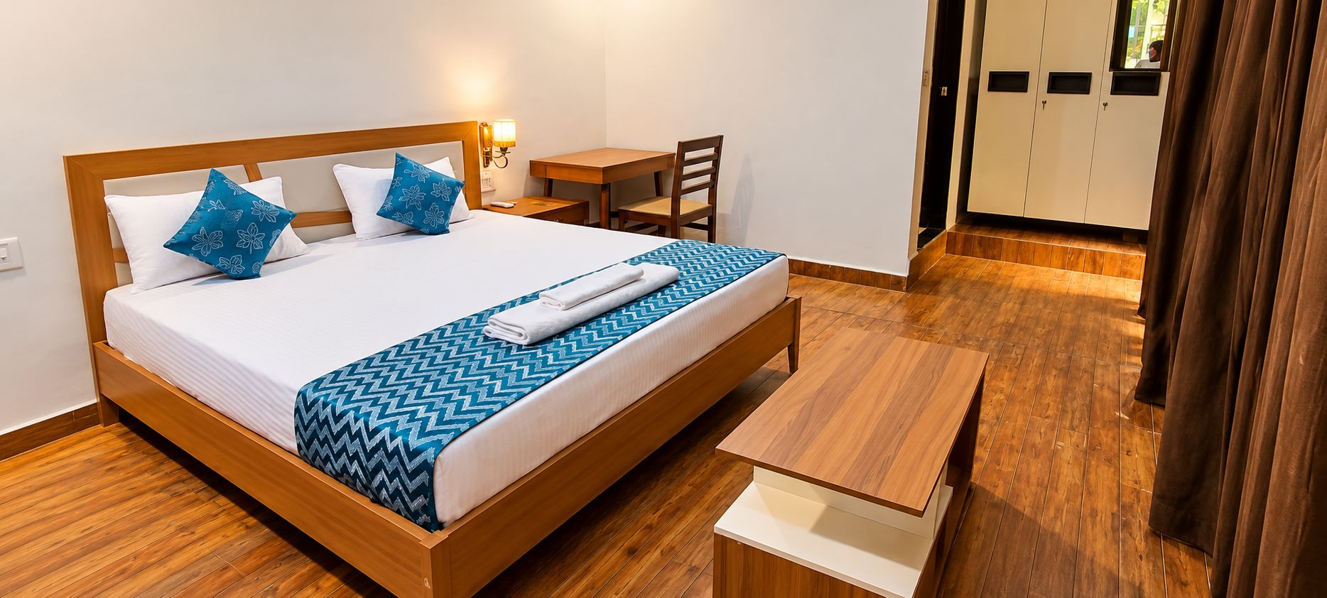 Una habitación de hotel con una cama de madera, un escritorio y una silla.