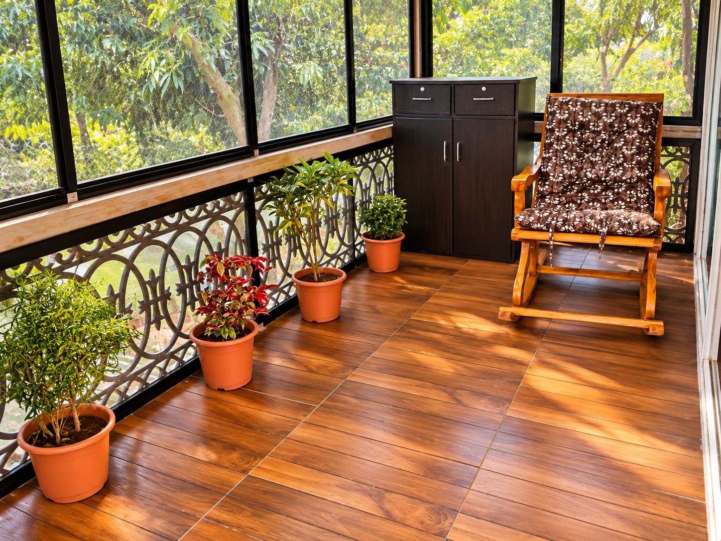 Un balcón con suelo de madera, plantas en macetas, una silla de madera y un mueble.