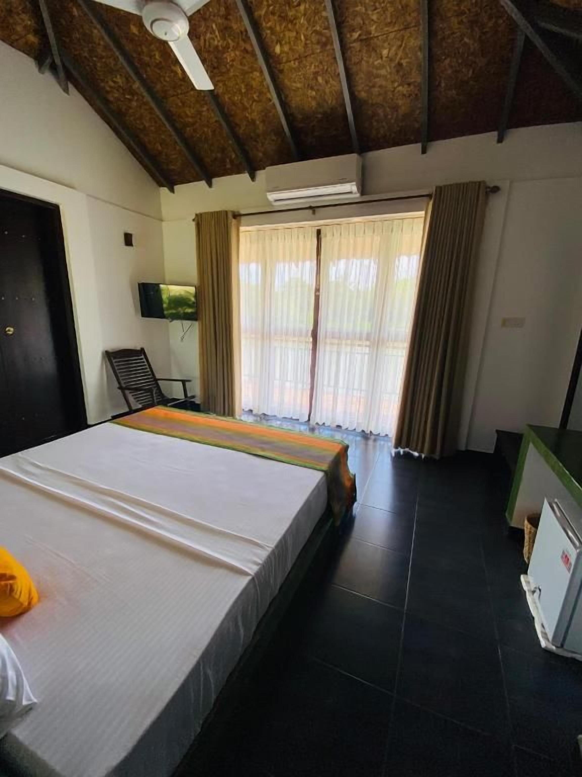 Una habitación con cama, escritorio, silla y televisión.
