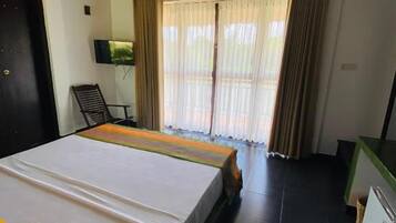 Una habitación con cama, escritorio, silla y televisión.