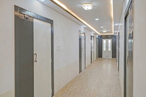 A long, narrow hallway with doors on both sides, a light-colored floor, and a ceiling with recessed lighting. - Hotel O Mr Crown Inn To Inn (Lucknow)