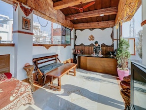 Quarto com um banco de madeira, área de bar e vista para a cidade.