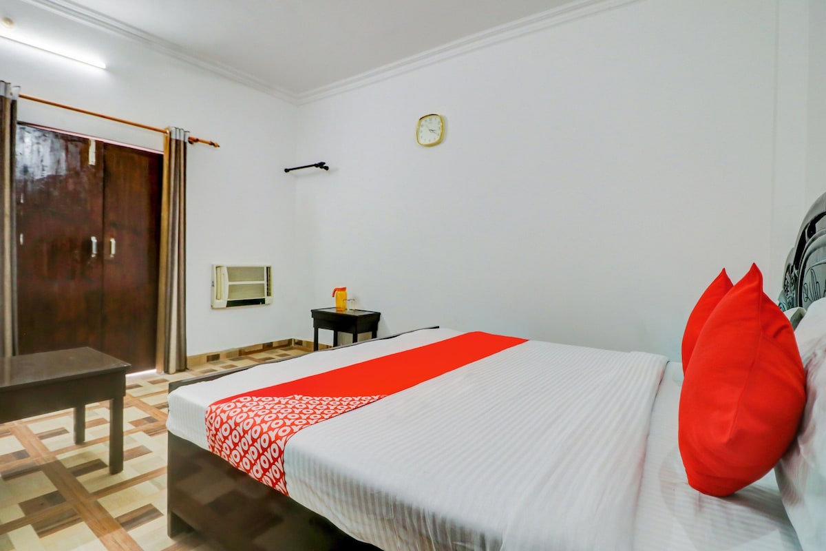 Ein Hotelzimmer mit einem Bett, einem kleinen Tisch, einer Uhr und einem Fenster.