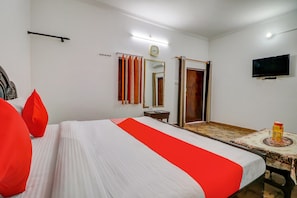 Ein Hotelzimmer mit Bett, Fernseher, Spiegel, einer Uhr und einem Fenster mit Vorhängen.