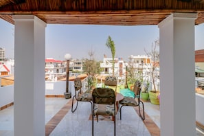 A covered outdoor seating area with two chairs and a table, surrounded by potted plants. - Hotel O Shanti Kuti Home Stay (Lucknow)