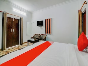 Ein Hotelzimmer mit Bett, Fernseher, Kleiderschrank und einer Sitzecke mit Sesseln.