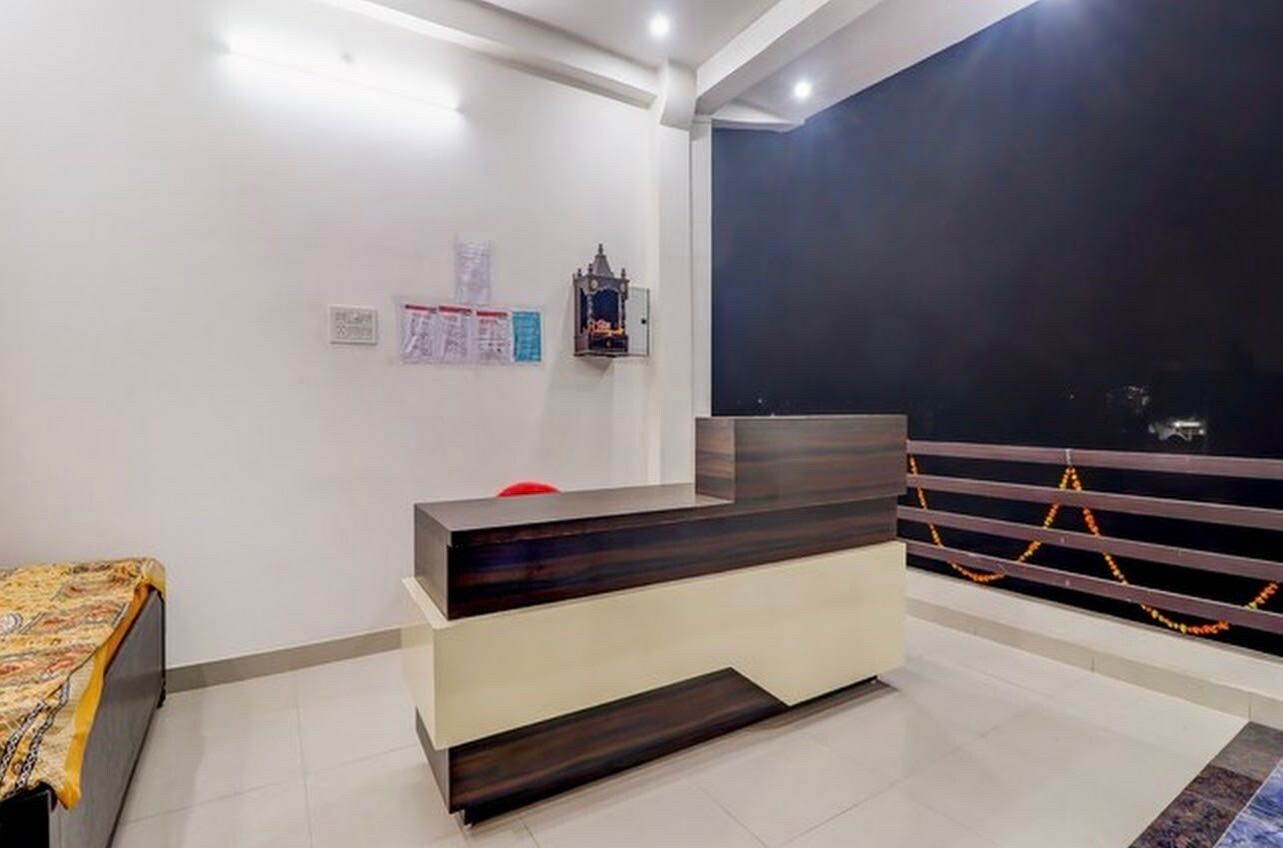 Una reception con una finitura in legno scuro, un bancone bianco e una sedia rossa. Sui muri, avvisi e un piccolo oggetto decorativo sopra la scrivania.