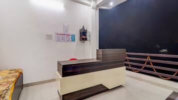 Una reception con una finitura in legno scuro, un bancone bianco e una sedia rossa. Sui muri, avvisi e un piccolo oggetto decorativo sopra la scrivania.