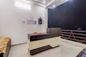 Una reception con una finitura in legno scuro, un bancone bianco e una sedia rossa. Sui muri, avvisi e un piccolo oggetto decorativo sopra la scrivania.