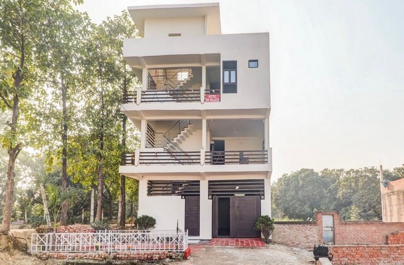 Un edificio a più piani con un balcone al secondo piano, una scala e un cartello che indica un albergo.