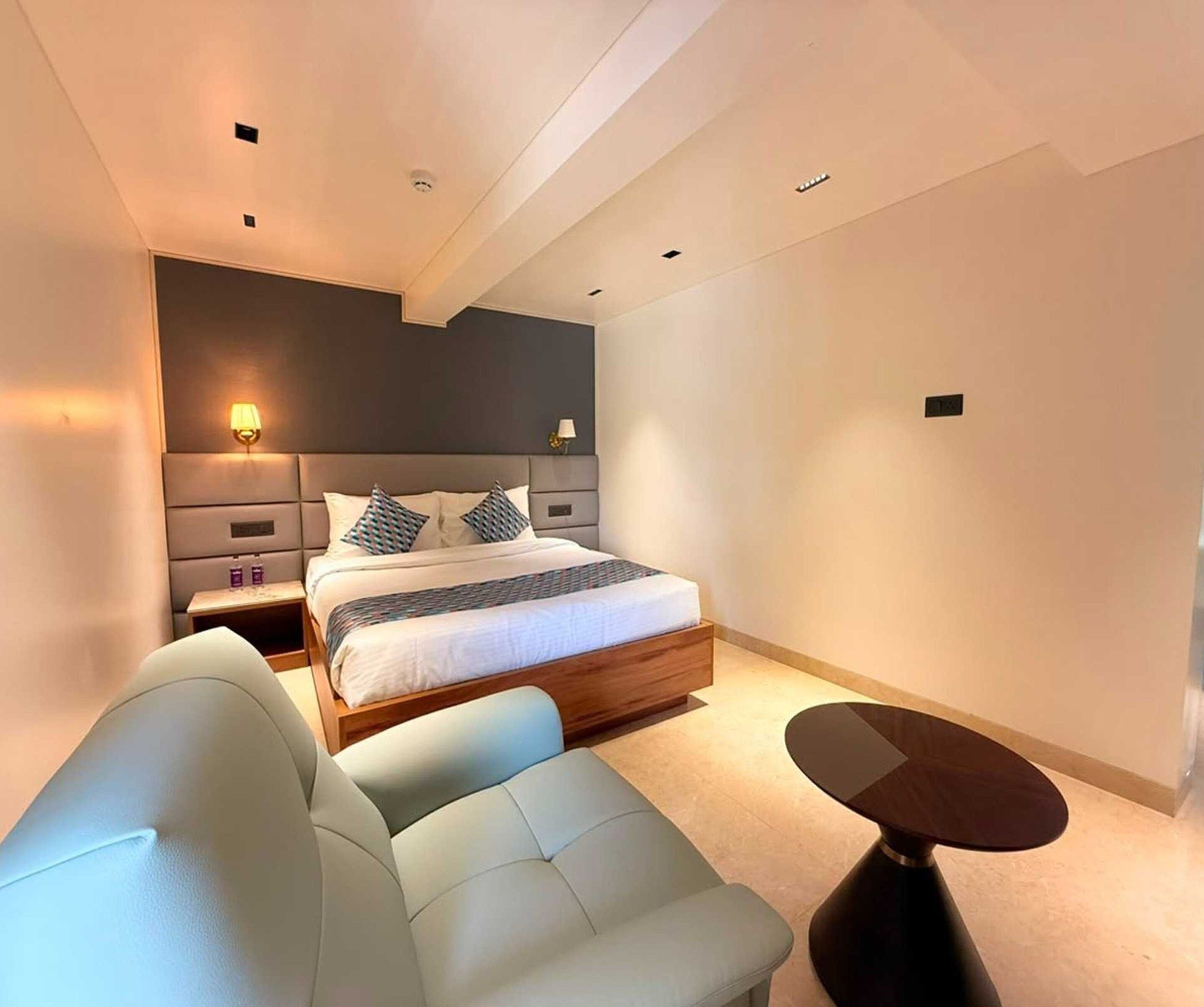 Un dormitorio moderno con cama, mesitas de noche, un sofá y una pequeña mesa.