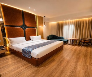 A hotel room with a large bed, a desk, and a chair. - Deluxe King Room Maneraa Homes (Tirupati)