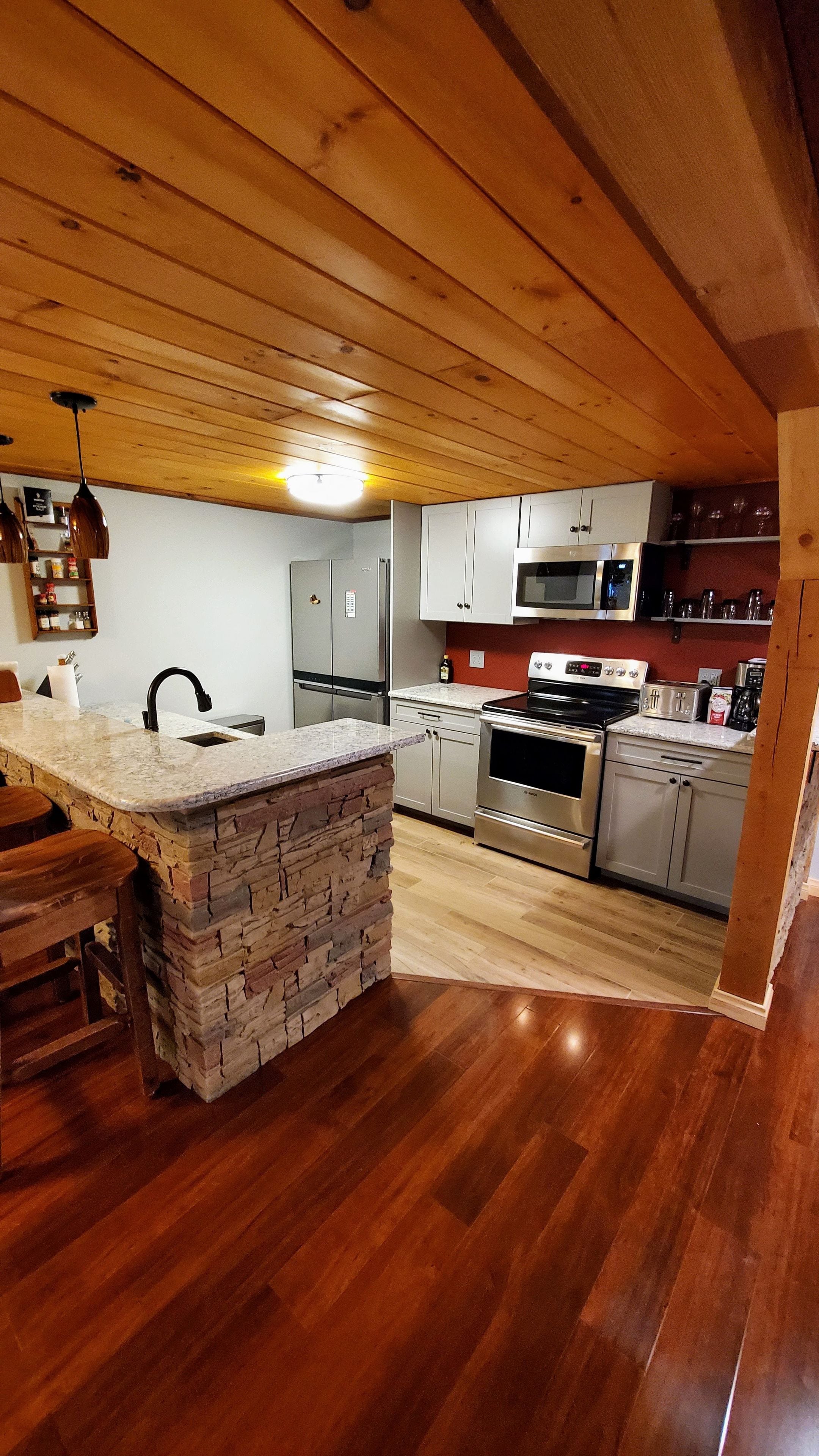 A kitchen with wooden cabinets, a granite countertop island, a built-in oven, and a microwave.