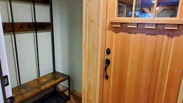 A wooden interior with a door, a bench, and a ceiling light.