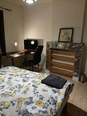 Ein Schlafzimmer mit Bett, Schreibtisch, Stuhl, Fernseher und Kamin.