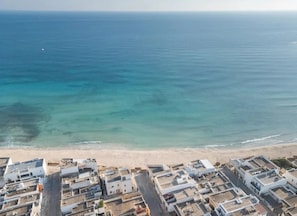 Vista aérea de uma área costeira com edifícios e uma praia.