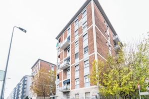 Un edificio residencial de varios pisos con balcones, una farola y una señal de límite de velocidad.