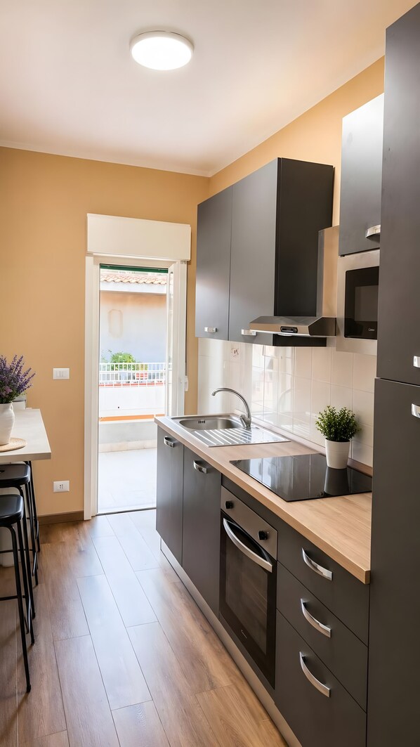 A modern kitchen with dark cabinetry, a stainless steel sink, and a built-in oven.