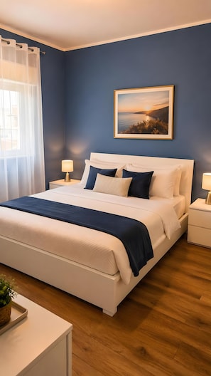 A bedroom with a bed, bedside tables, a lamp, a framed picture on the wall, and a window with curtains.