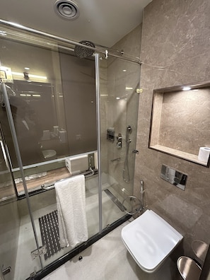 A modern bathroom with a glass-enclosed shower, a white sink, and a marble-tiled wall. - Met City Club & Convention Centre (Yakubpur)