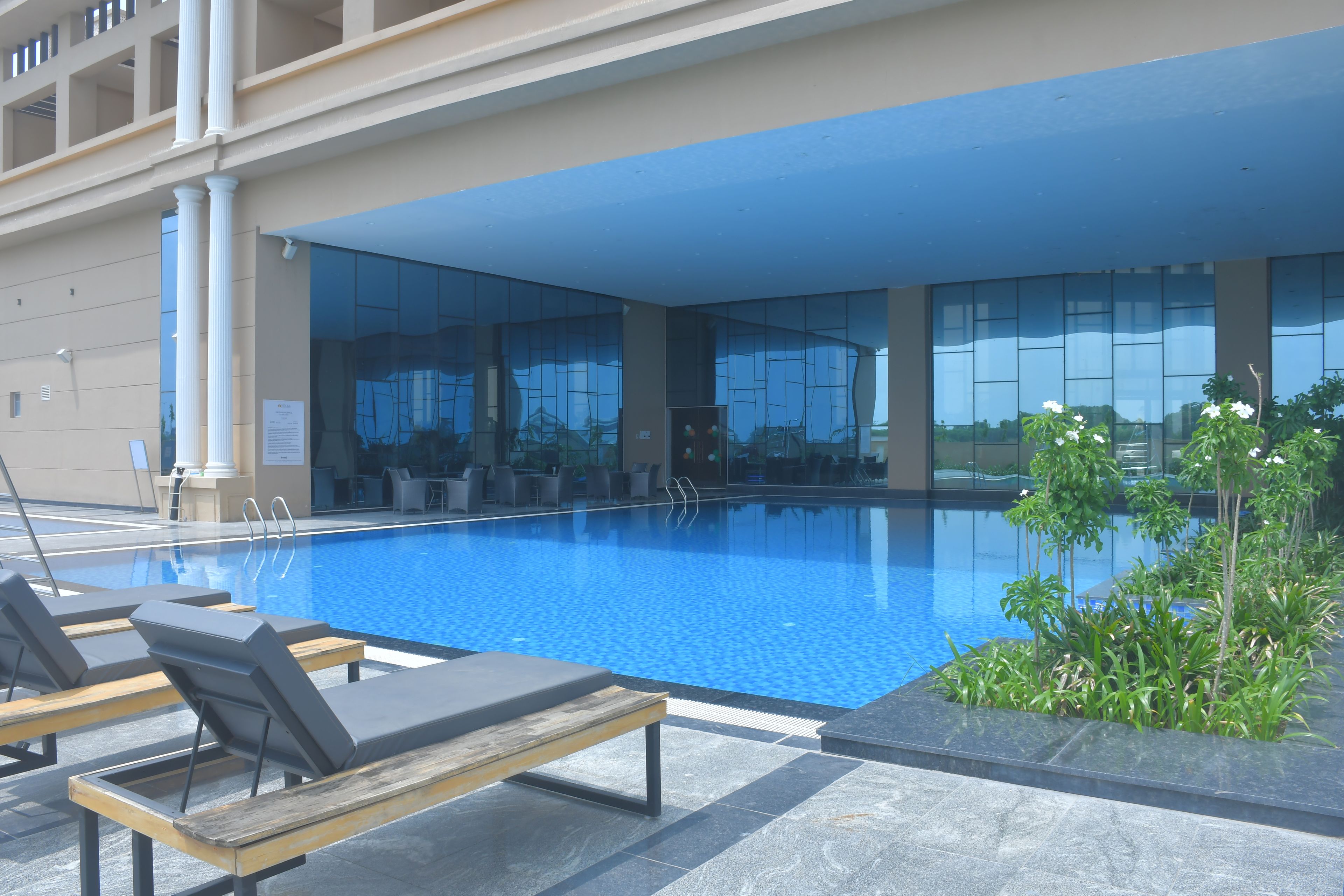 A swimming pool with lounge chairs and a glass wall.