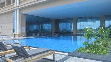 A swimming pool with lounge chairs and a glass wall.