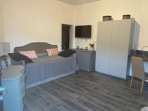 Ein Schlafzimmer mit Bett, Kleiderschrank, Schreibtisch und Fernseher.