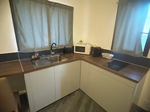 Eine kleine Küche mit Spüle, Toaster, Mikrowelle und Wasserkocher.