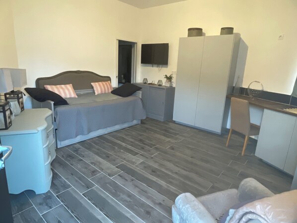 Ein gemütliches Schlafzimmer mit Bett, Nachttisch, Kleiderschrank und einer kleinen Küchenzeile.