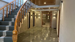 Una escalera con barandas de madera y suelo pulido que conduce a una habitación con paredes de piedra e iluminación empotrada.