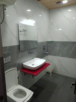 Un baño moderno con un lavamanos blanco, un espejo, una ducha y un inodoro.