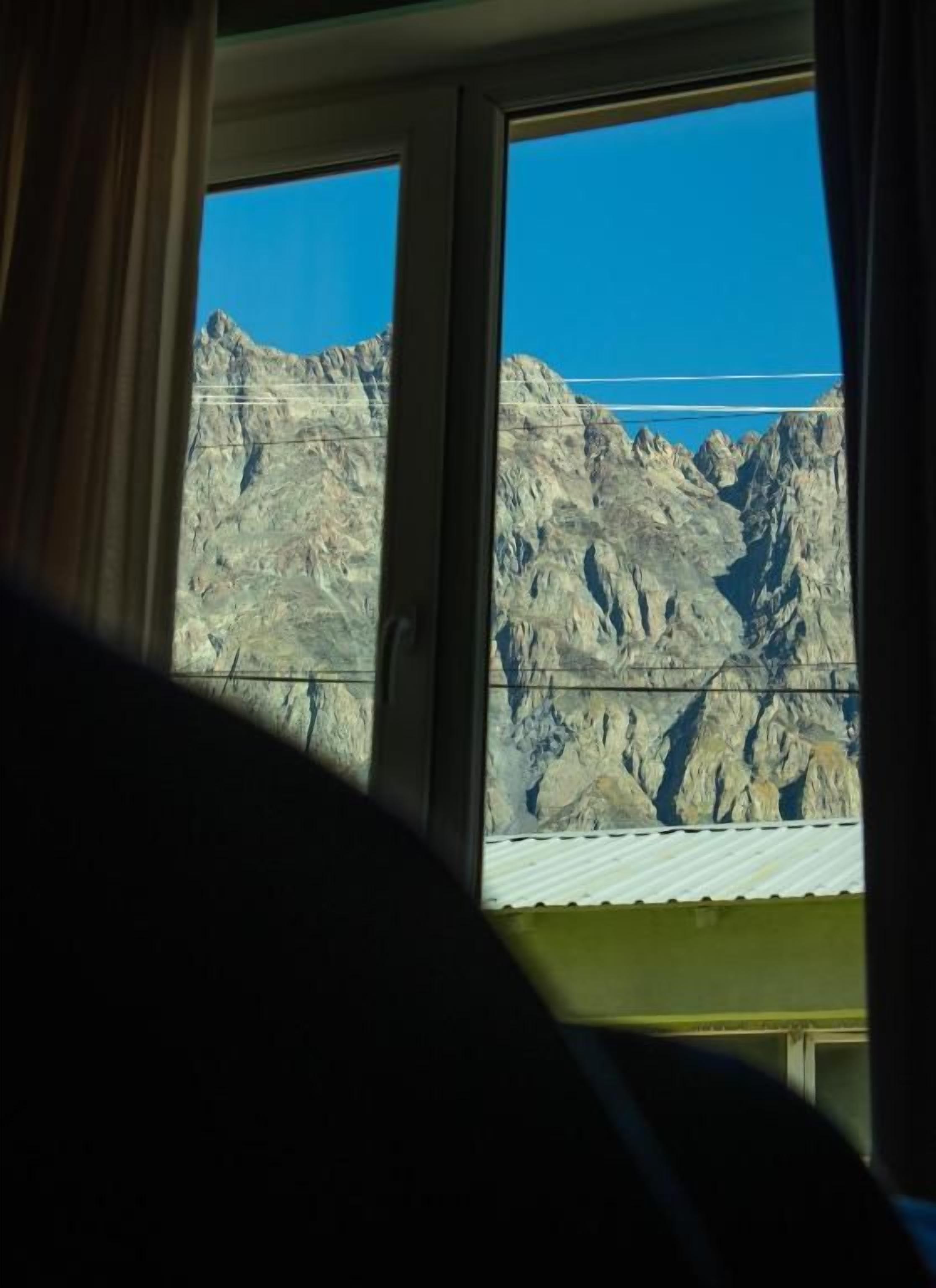 Une fenêtre donnant sur des montagnes rocheuses.