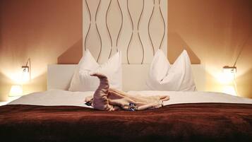 A hotel room with a bed, pillows, a blanket, and two bedside lamps.