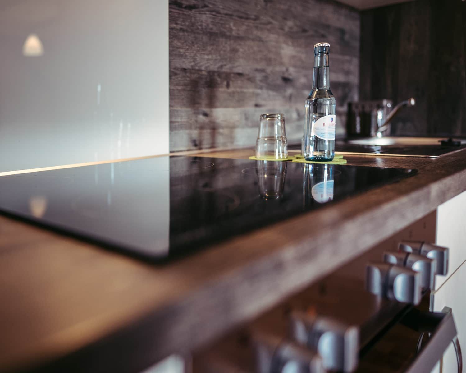 Una encimera de cocina con una botella, un vaso y un grifo.
