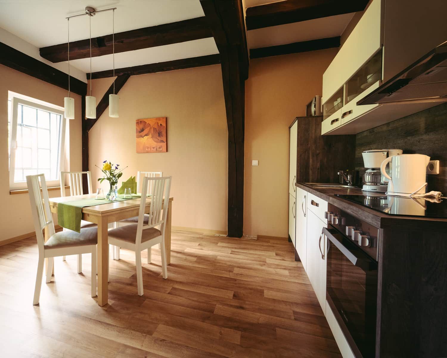 Una cocina con armarios de madera, estufa y comedor con sillas y mesa.