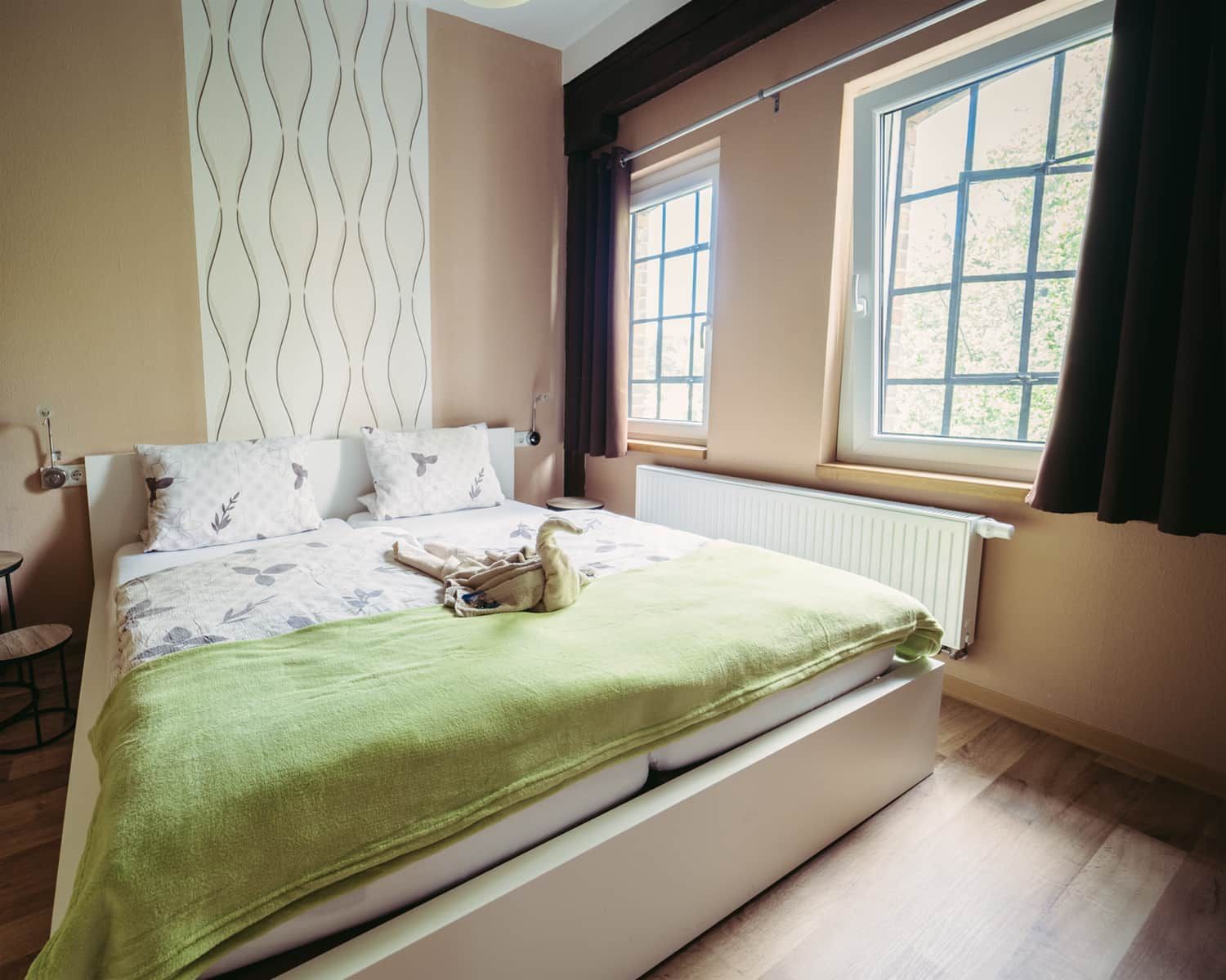 Ein Schlafzimmer mit einem Bett, einem Heizkörper, einem Fenster und einer Wand mit einem Wellenmuster.