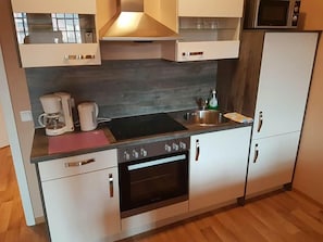 Eine kompakte Küche mit Einbauofen, Kaffeemaschine und Mikrowelle.