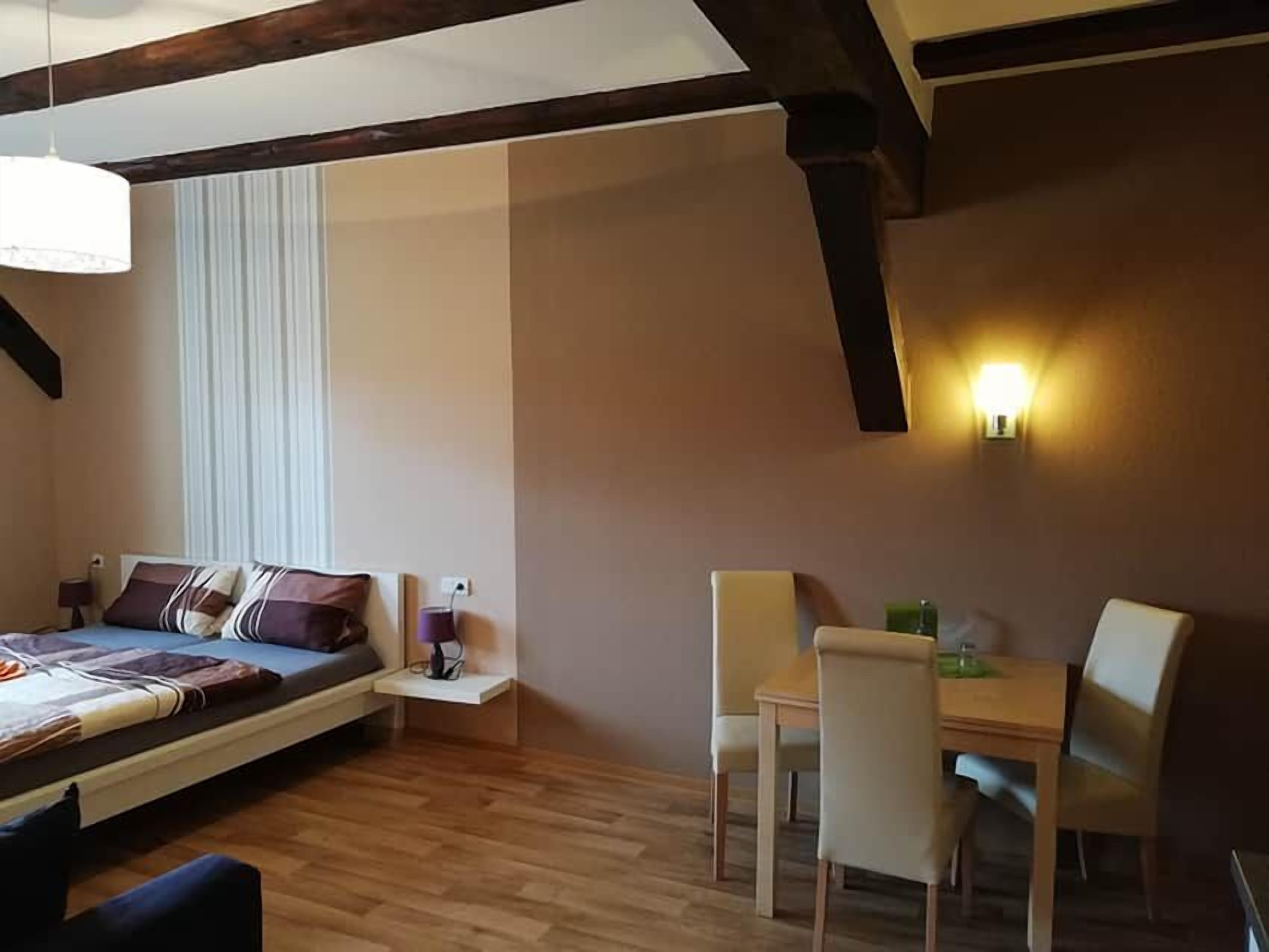 Ein Schlafzimmer mit einem Bett, einem Nachttisch, einer Lampe und einem Essbereich mit Stühlen und einem Tisch.