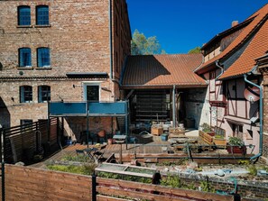 Ein Innenhof mit einer Holzterrasse, Ziegelbauten und einem roten Ziegeldach.