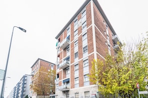 Un edificio de varios pisos con balcones, una farola y una señal de tráfico que indica un límite de velocidad de 30.