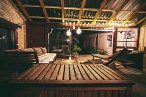 Eine rustikale Holzterrasse mit einer Bank, einem Tisch und einer hängenden Leuchte.