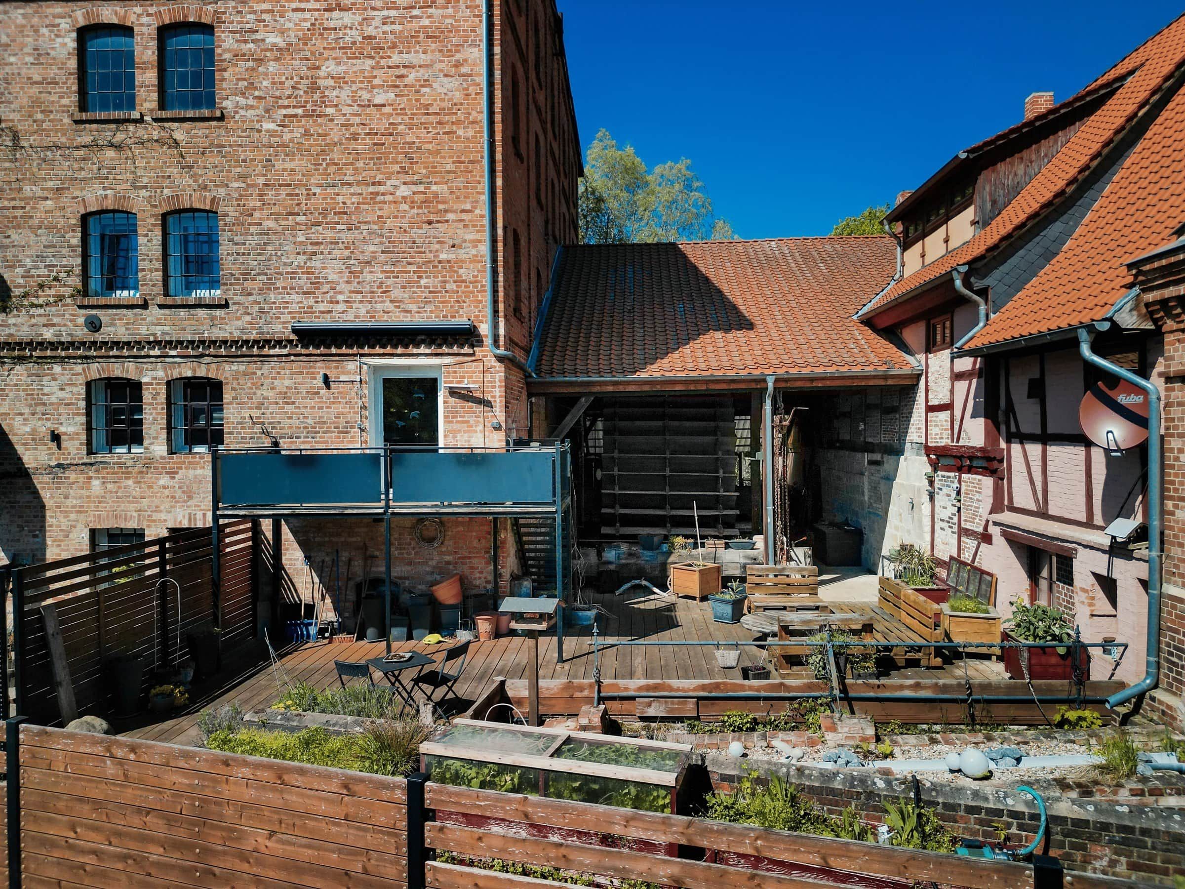 Ein Innenhof mit einer Holzterrasse, Ziegelbauten und einem roten Ziegeldach.