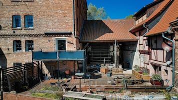 Ein Innenhof mit einer Holzterrasse, Ziegelbauten und einem roten Ziegeldach.