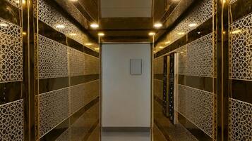 A modern elevator interior with patterned walls and ceiling lights.