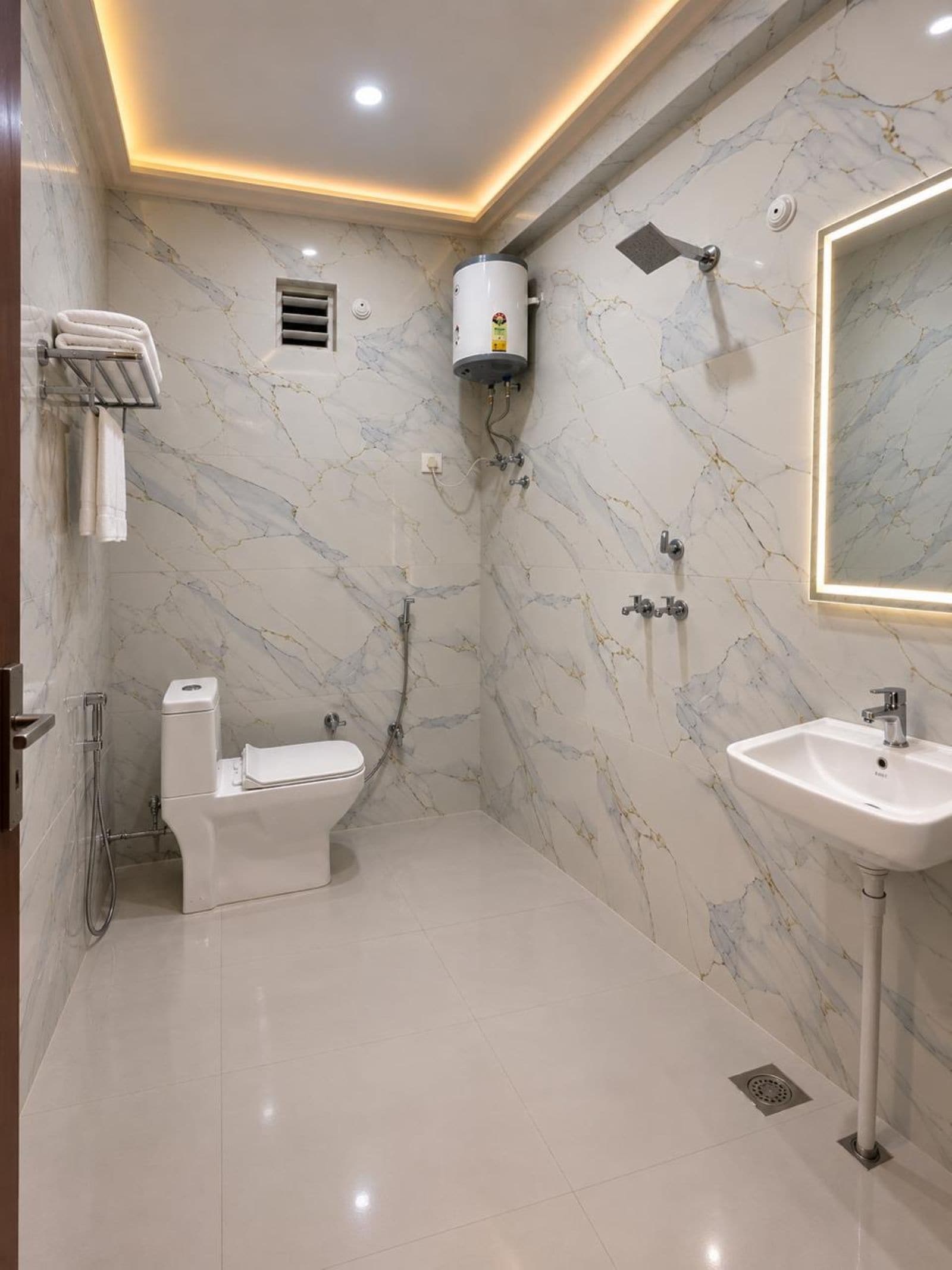 A bathroom with a toilet, shower, and sink, all against marble walls.