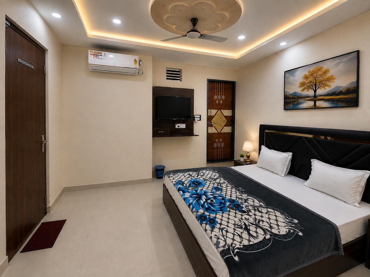A bedroom with a bed, a television, a ceiling fan, and a painting on the wall.